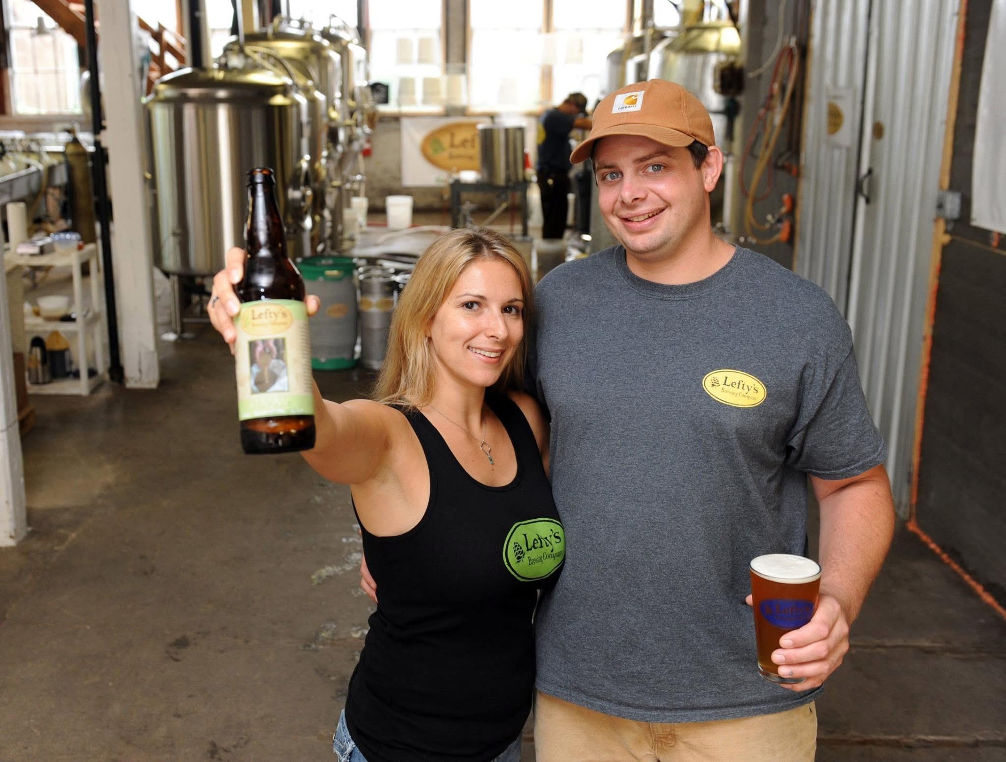 A Man and a Woman holding beer smiling at the camera