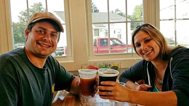 A Man and a Woman holding beer smiling at the camera